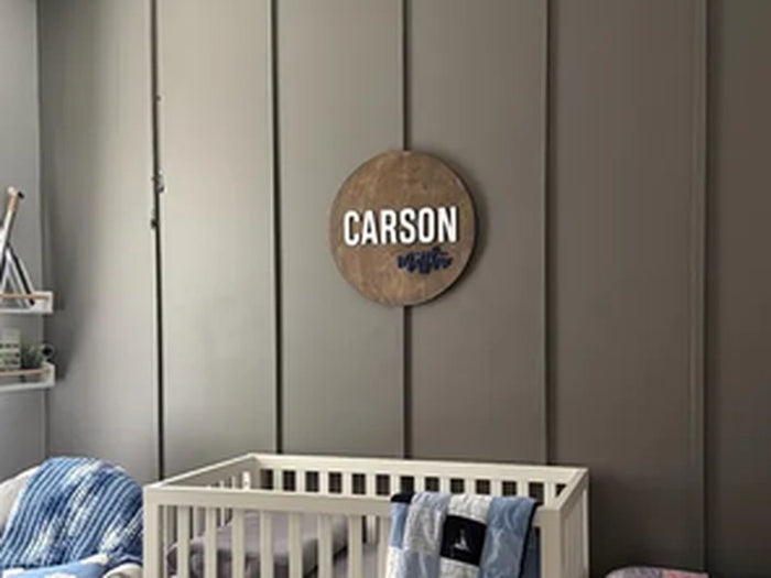 Round wooden Carson name sign above a crib