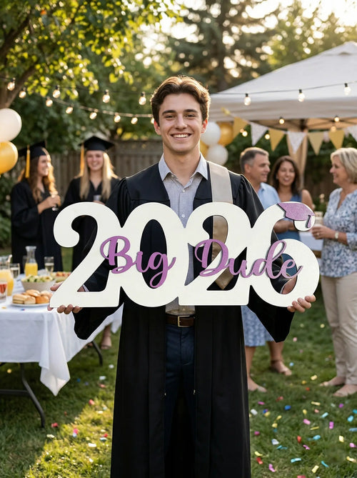 Graduate holding '2026 Big Dude' sign at a graduation party outdoors.