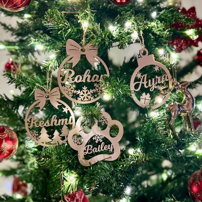 Personalized wooden name ornaments, including a paw print, on a Christmas tree