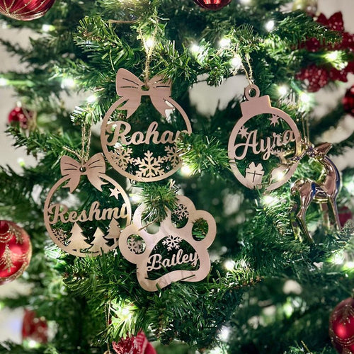 Personalized wooden name ornaments, including a paw print, on a Christmas tree