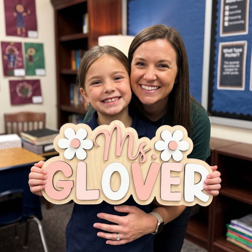Teacher and student holding a pink and white classroom name sign